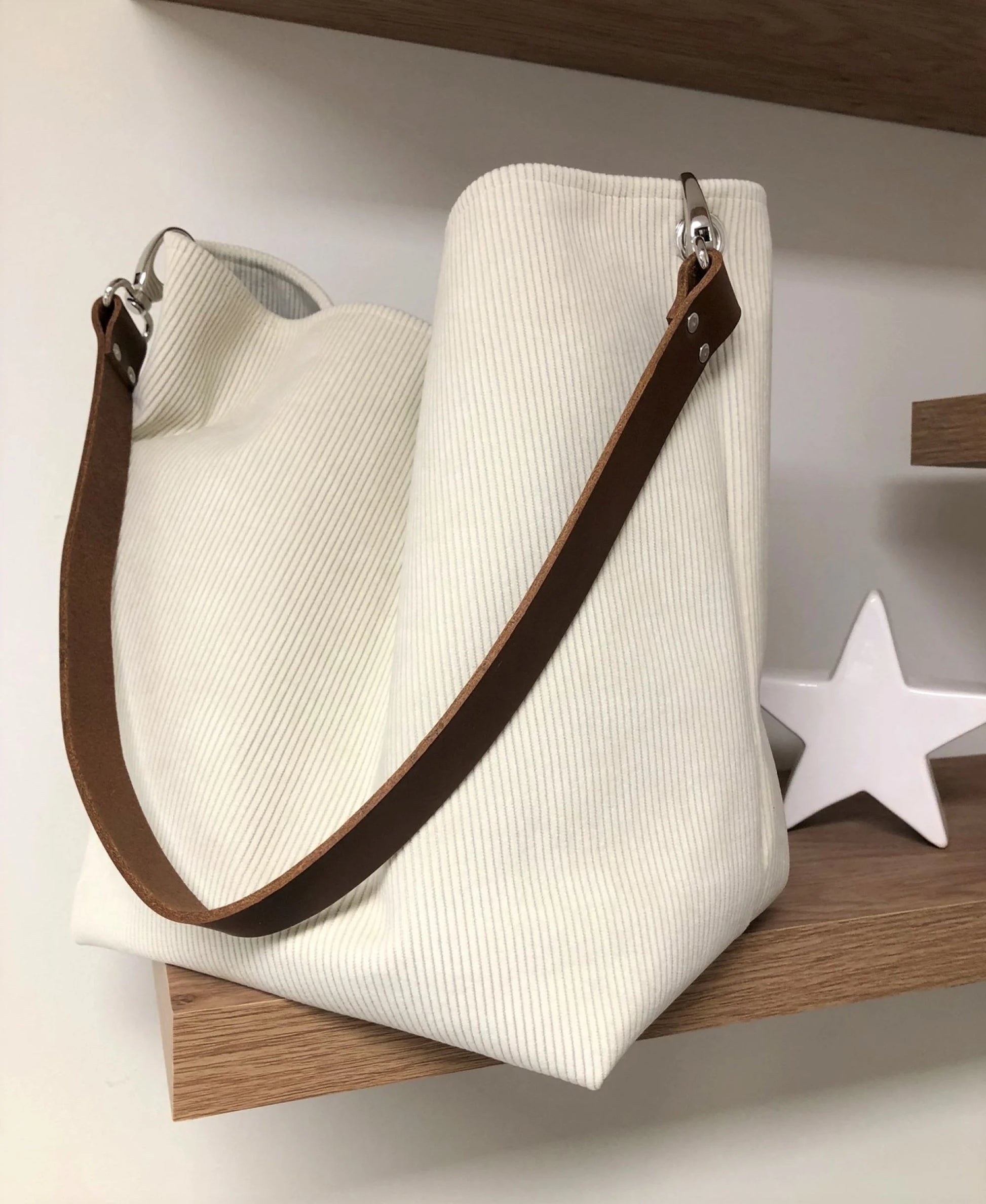 Le sac hobo en velours cotelé ivoire et son anse en cuir marron.