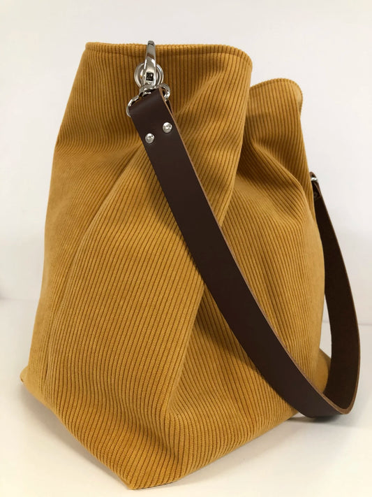 Le sac hobo en velours cotelé jaune moutarde et son anse en cuir marron.