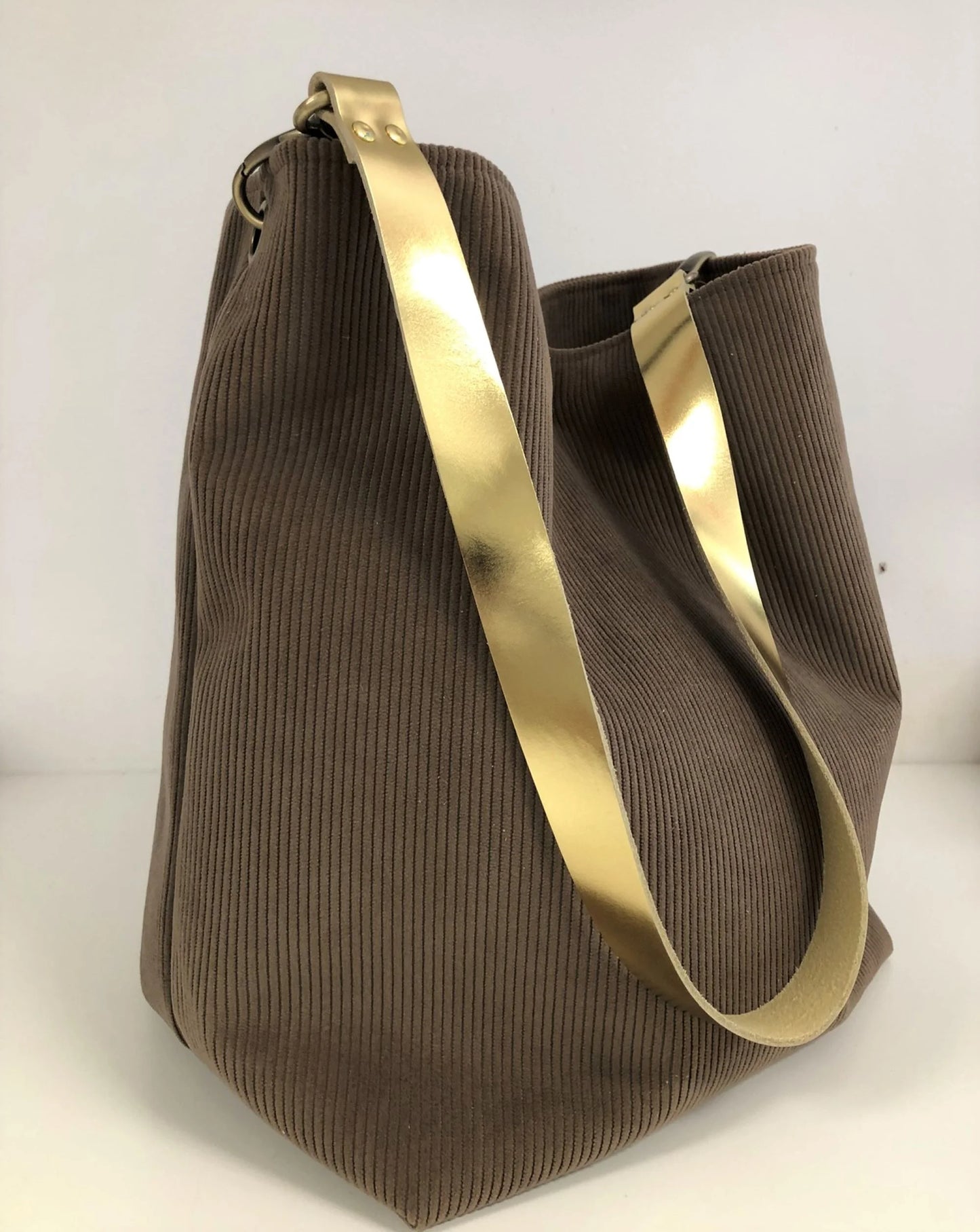 Le sac hobo en velours cotelé marron chamois et son anse en cuir doré