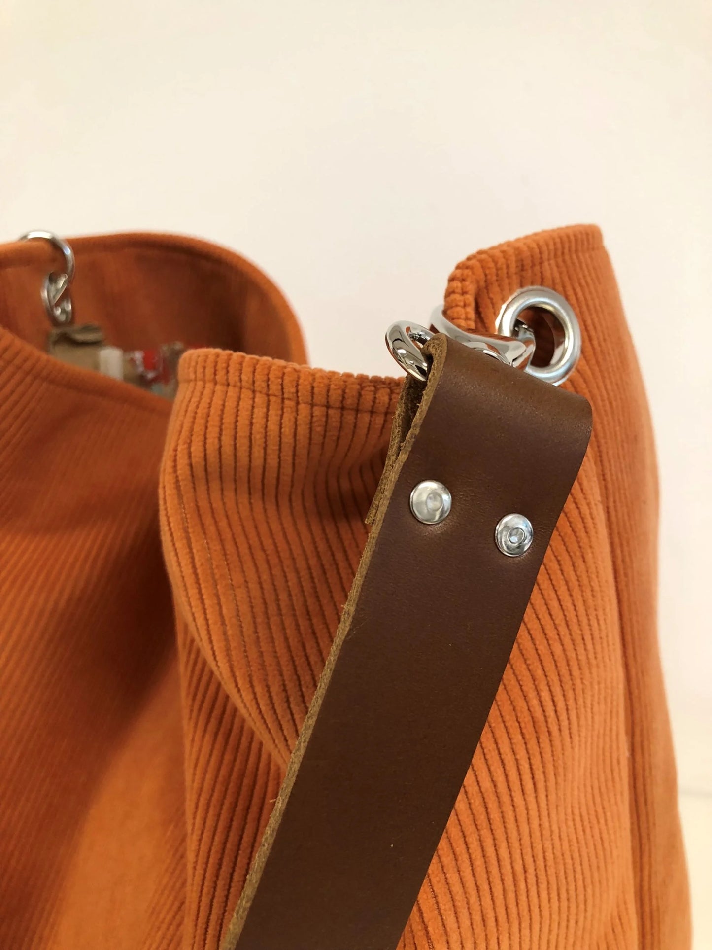 Vue détaillée de l'anse en cuir marron du sac hobo Lesfilsdisa en velours côtelé orange