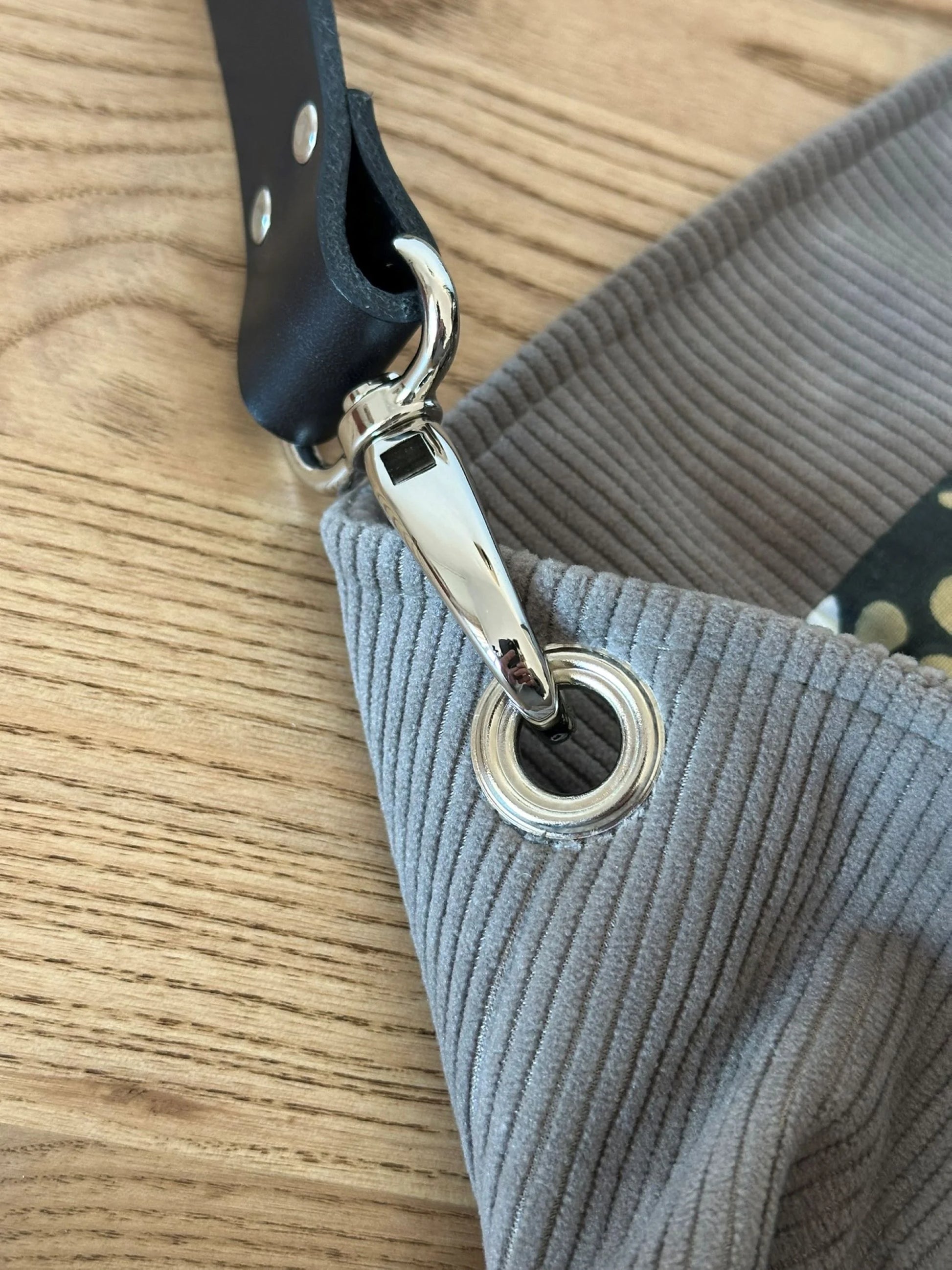 Le mousqueton de l'anse en cuir du sac Hobo en velours cotelé taupe.