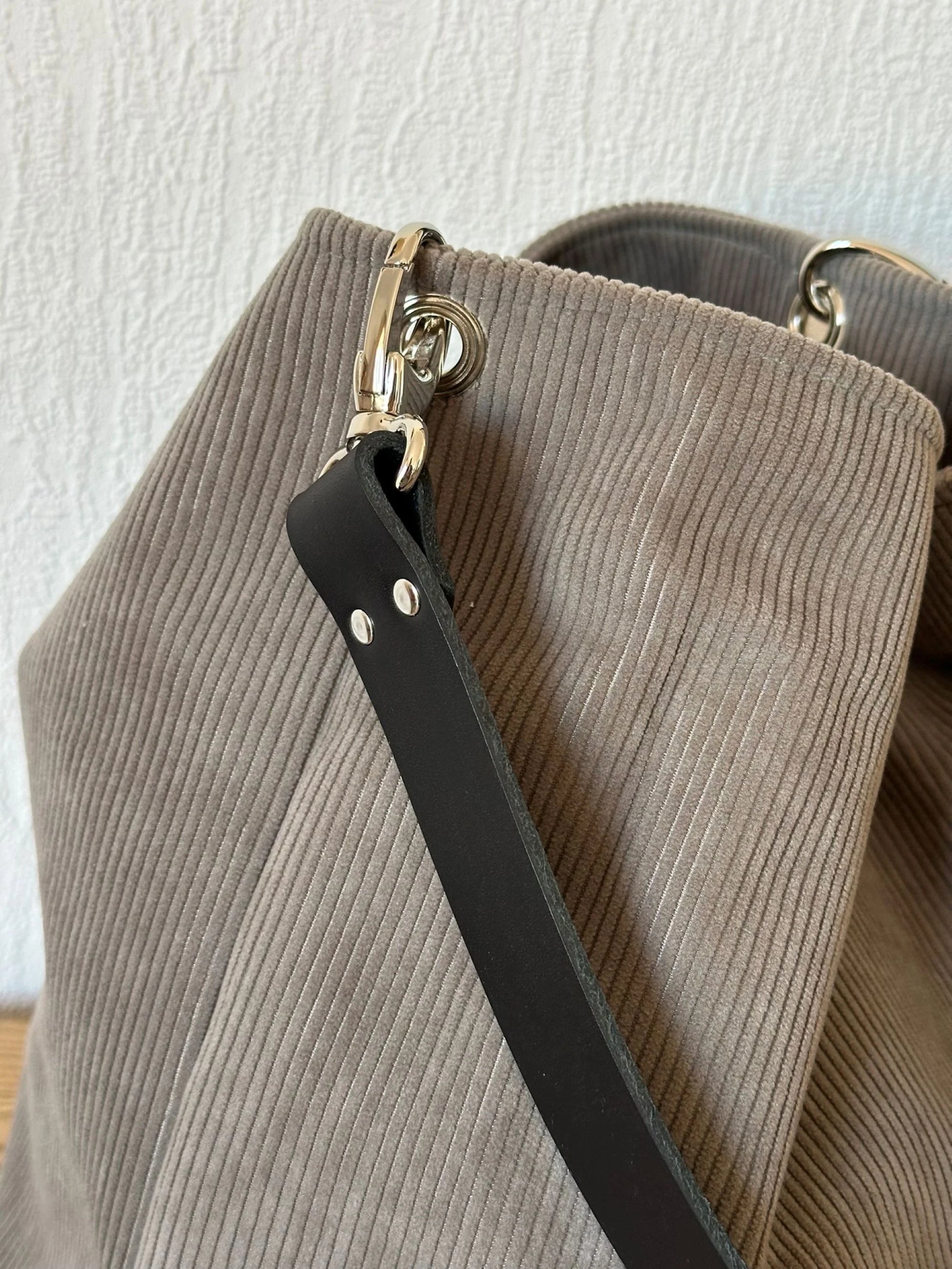 L'anse en cuir noir amovible du sac Hobo en velours cotelé taupe.