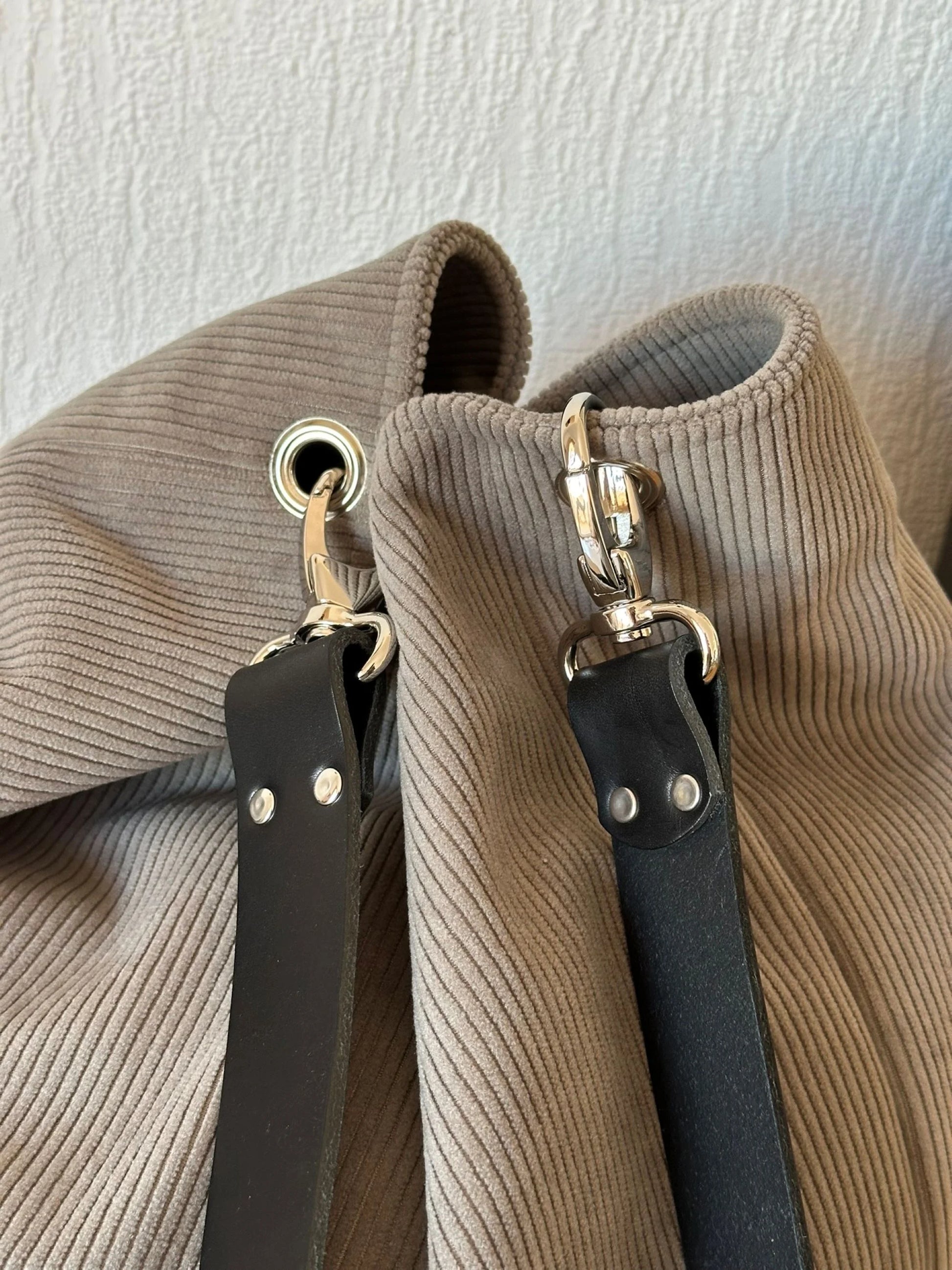 L'anse en cuir noir rivetée et amovible du sac Hobo en velours cotelé taupe.