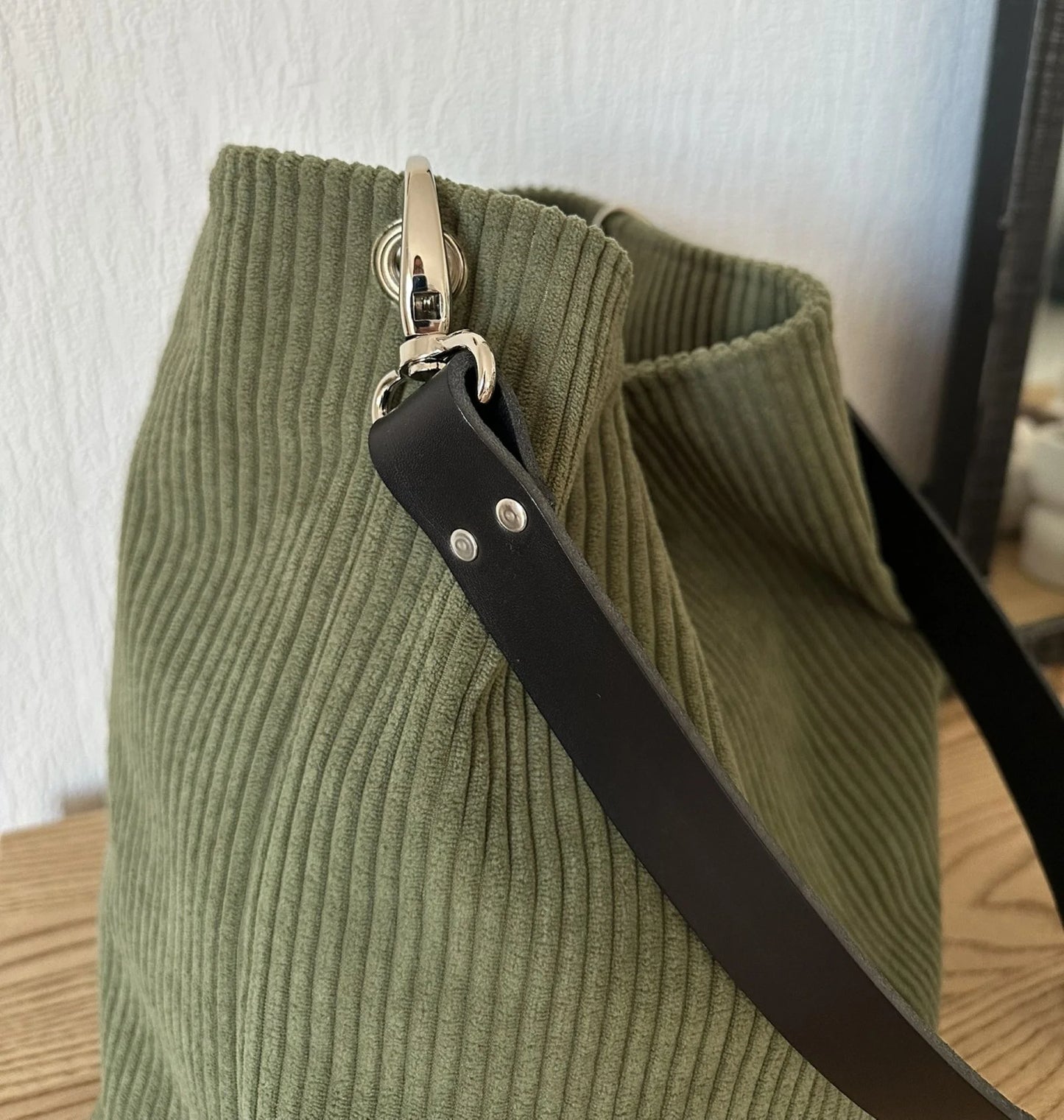 L'attache de l'anse en cuir du sac Hobo en velours cotelé vert armée.