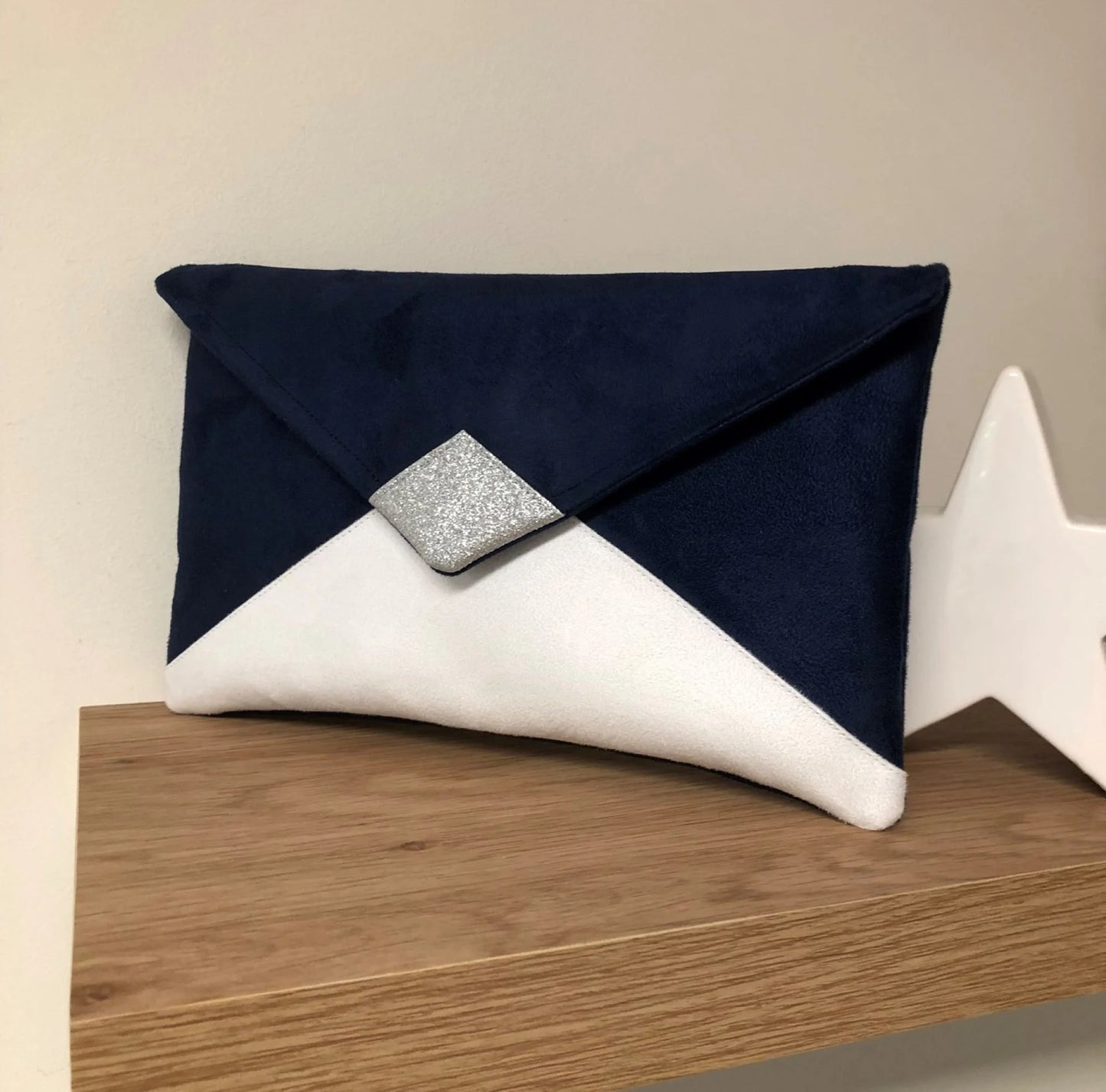 Le sac pochette Isa bleu marine et blanc à paillettes argentées, sans chainette amovible.