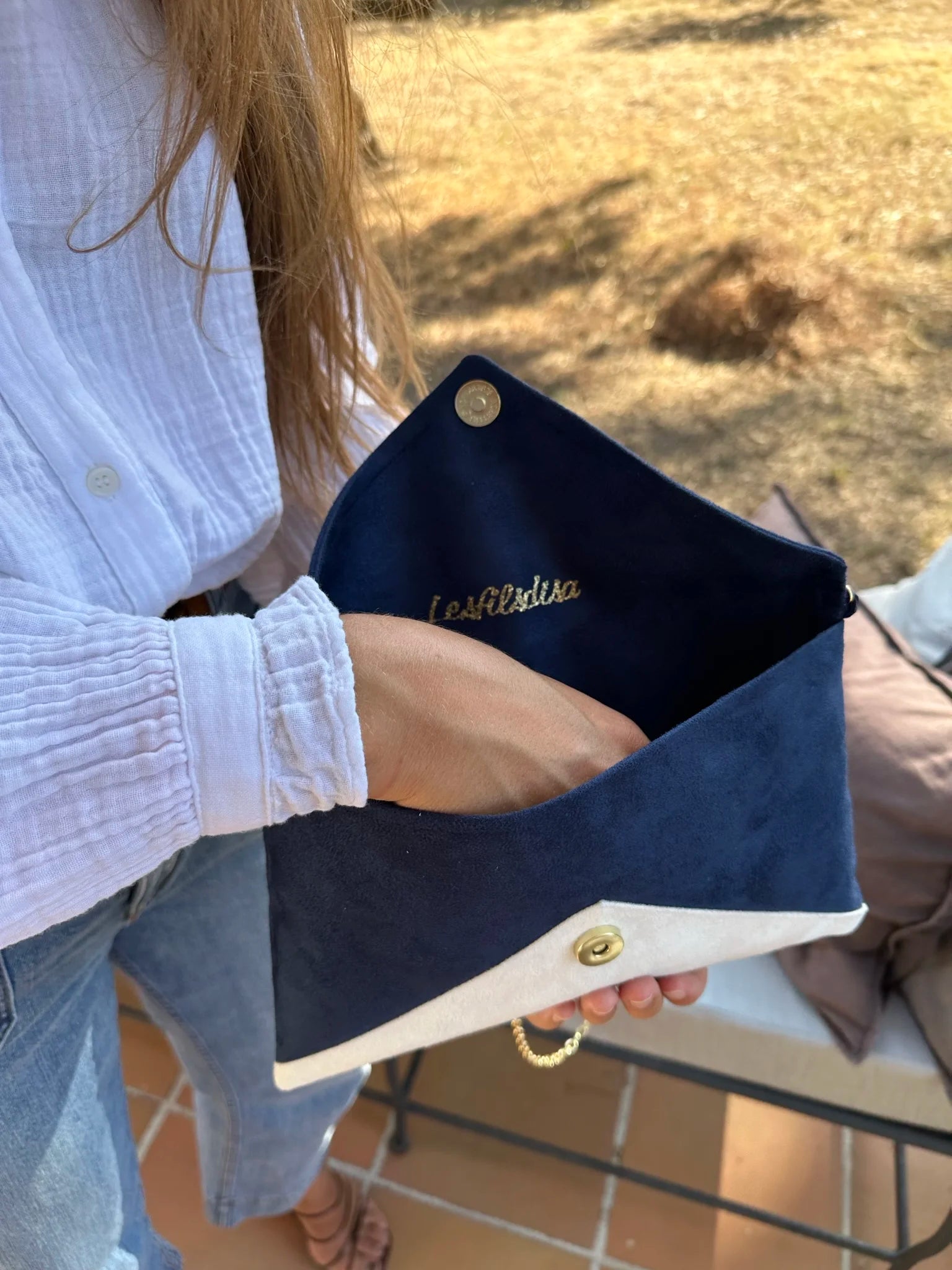 Femme qui ouvre le sac pochette Isa bleu marine et blanc à paillettes dorées.