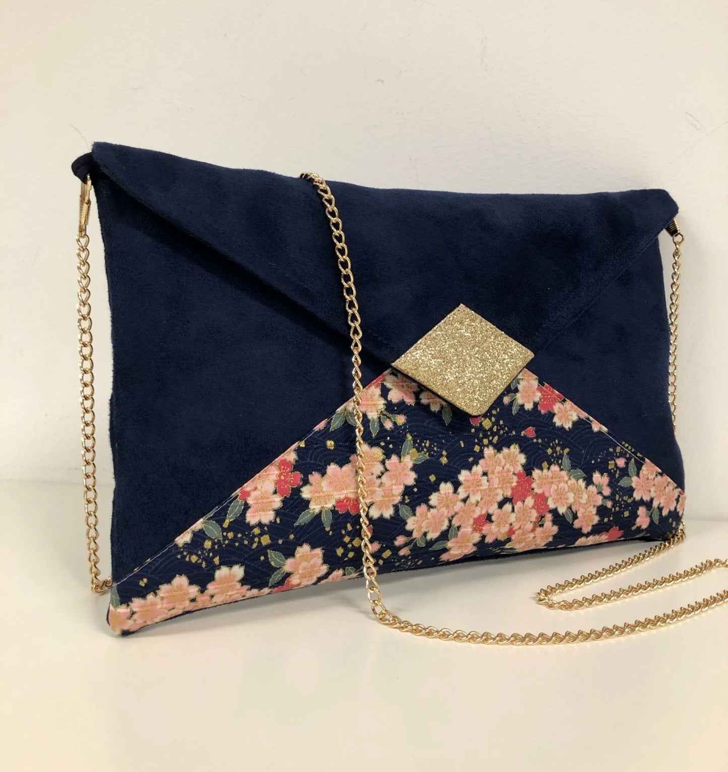 Face avant du sac pochette Isa bleu marine à fleurs de cerisier et paillettes dorées.