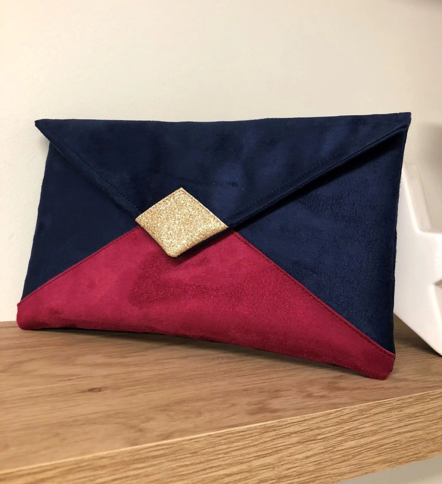 Le sac pochette Isa bleu marine et fuchsia à paillettes dorées, sans chainette amovible.