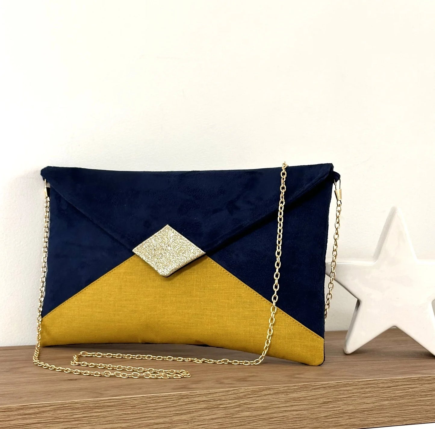 Le sac pochette Isa bleu marine et jaune moutarde à paillettes dorées, avec sa chainette amovible.