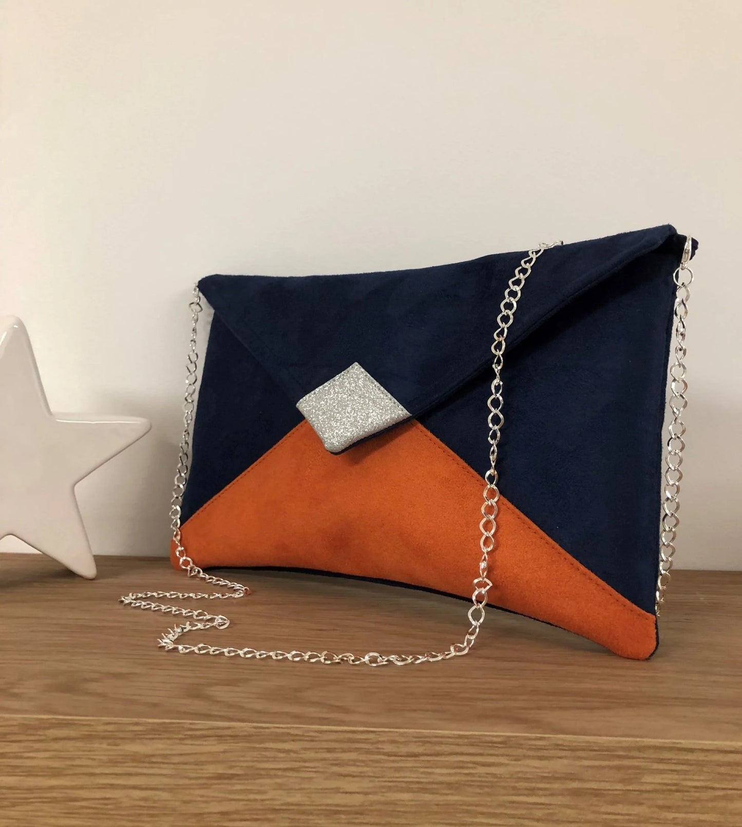 Le sac pochette Isa bleu marine et orange à paillettes argentées, avec chainette amovible.