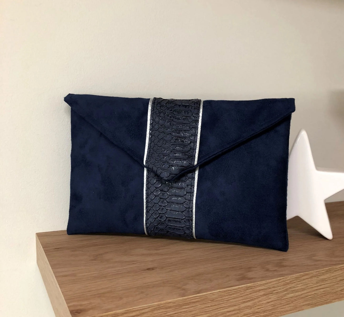 Le sac pochette Isa bleu marine reptile à liseré argenté, sans chainette amovible.