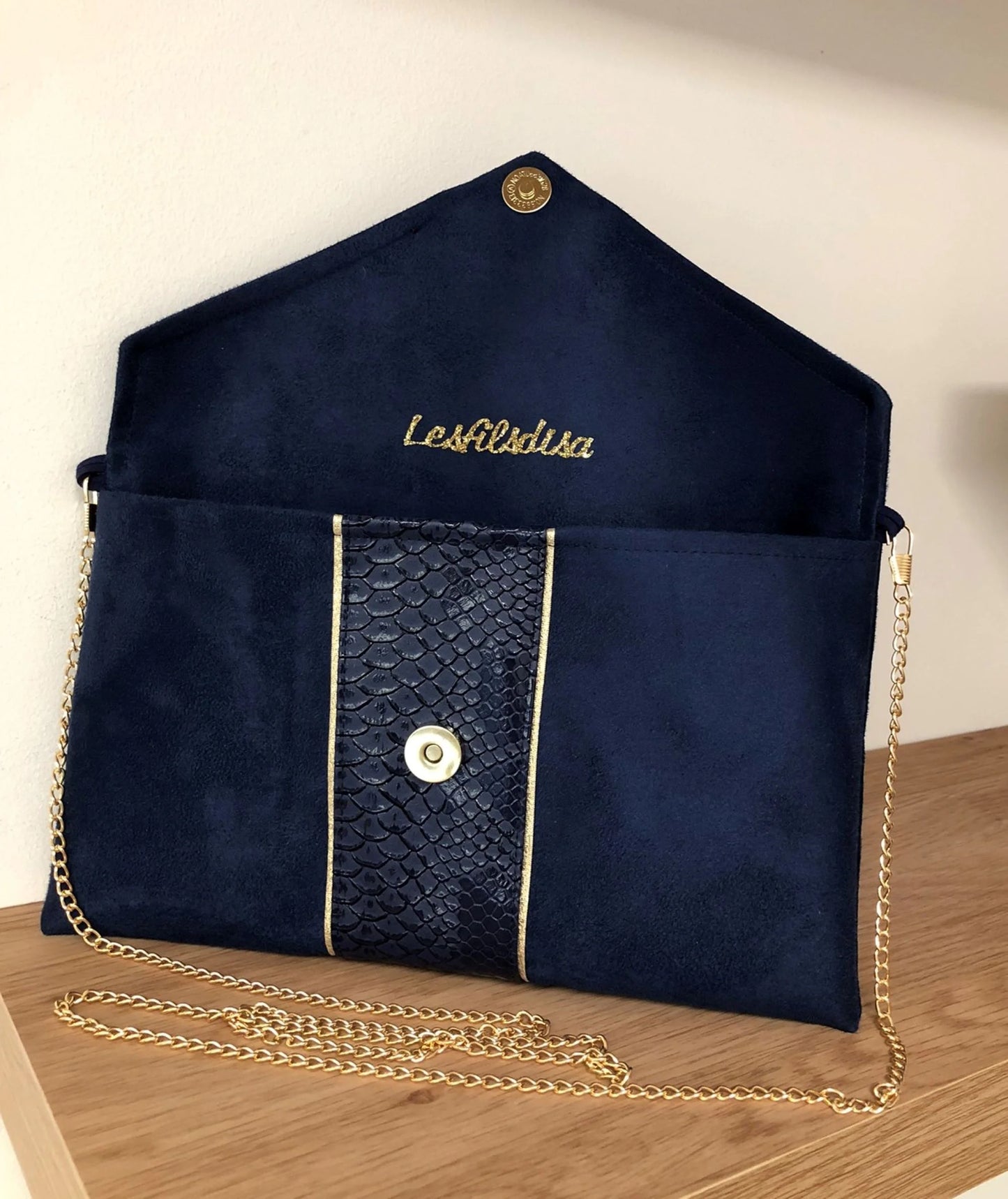 Le sac pochette Isa bleu marine reptile à liseré doré, ouvert.