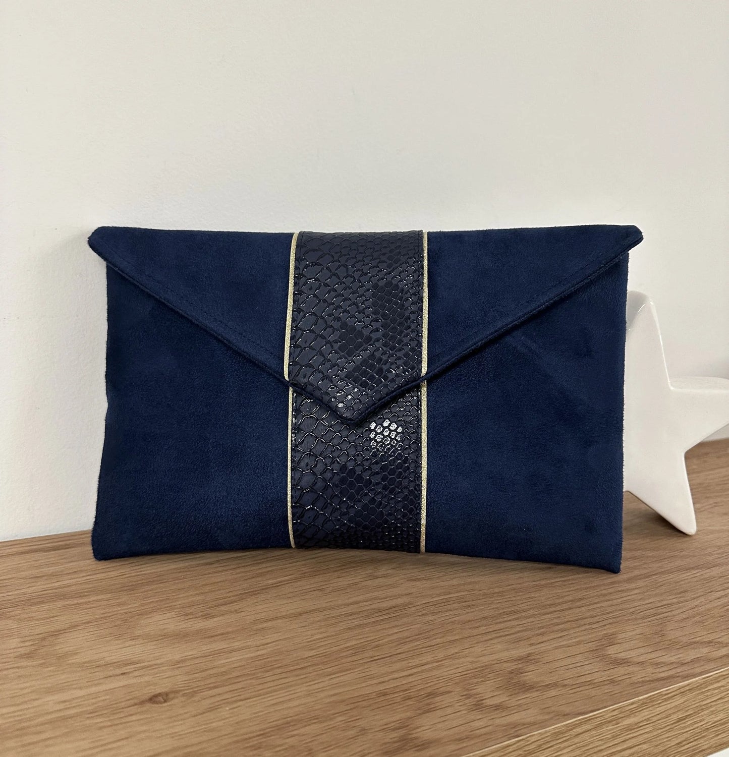Le sac pochette Isa bleu marine reptile à liseré doré, sans chainette.