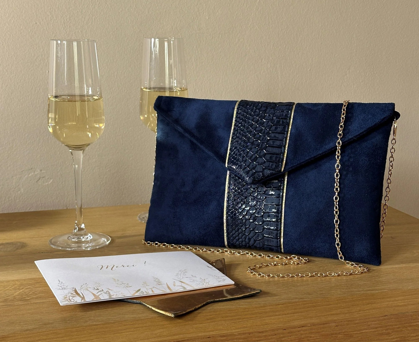 Le sac pochette Isa bleu marine reptile à liseré doré, vue de face.