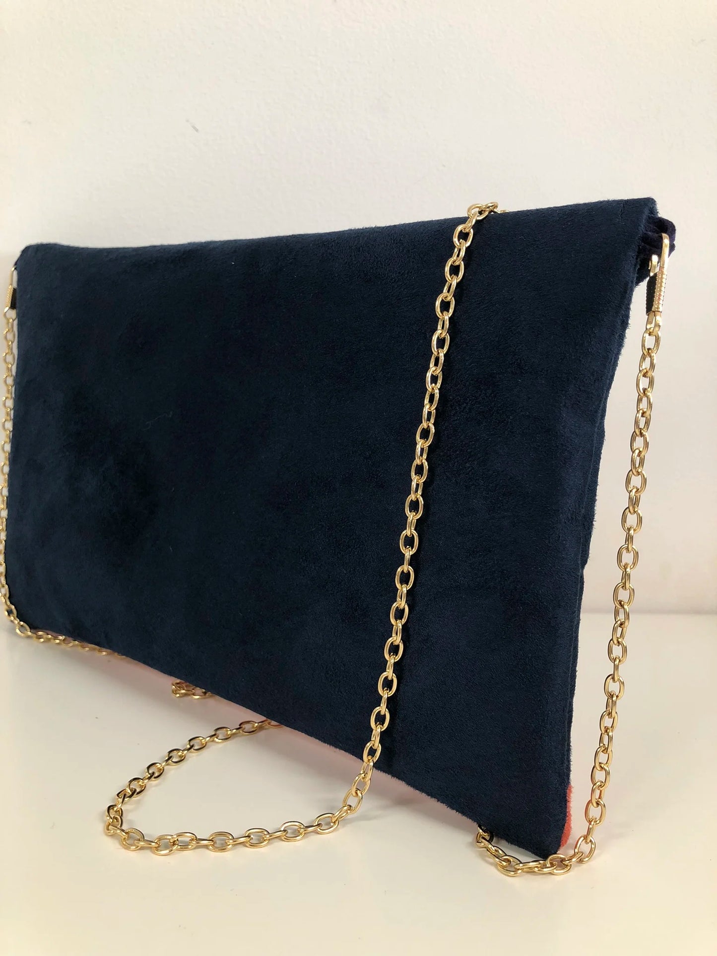 Vue arrière du sac pochette Isa bleu marine et rouge à paillettes dorées.