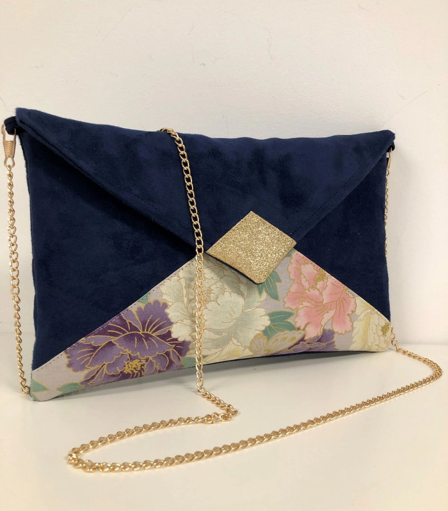 Le sac pochette Isa bleu marine en tissu japonais à fleurs mauve et rose et paillettes dorées.