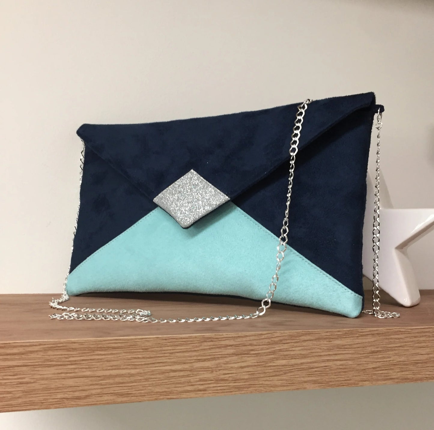 Le sac pochette Isa bleu marine et vert menthe à paillettes argentées, avec chainette amovible.