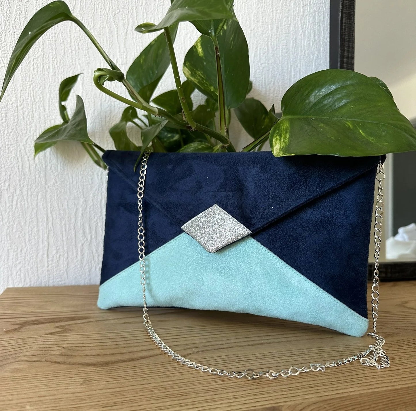 Le sac pochette Isa bleu marine et vert menthe à paillettes argentées, avec chainette amovible.