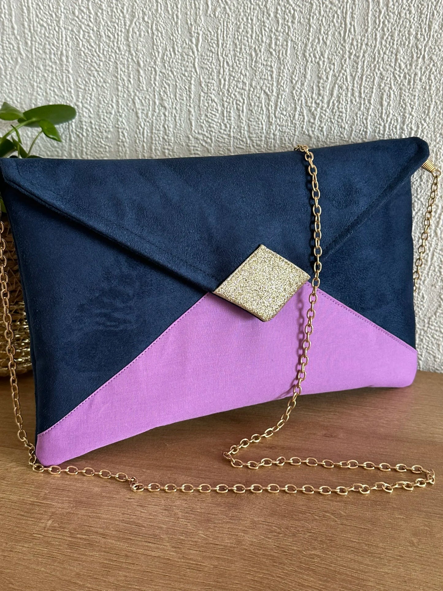 Face avant du sac pochette Isa bleu marine violet et doré avec sa chainette dorée amovible.
