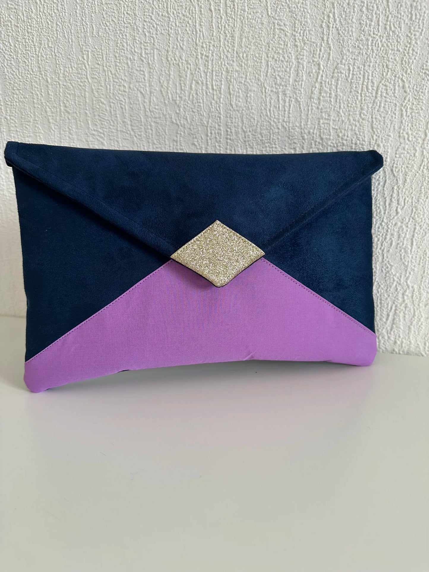 Le sac pochette Isa bleu marine violet et doré sans chainette dorée amovible.