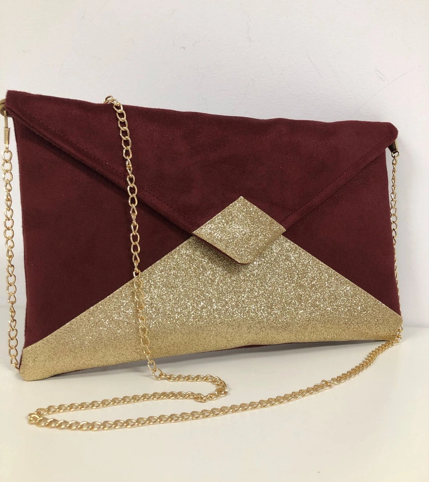 Le sac pochette Isa bordeaux à paillettes dorées, avec chainette amovible.
