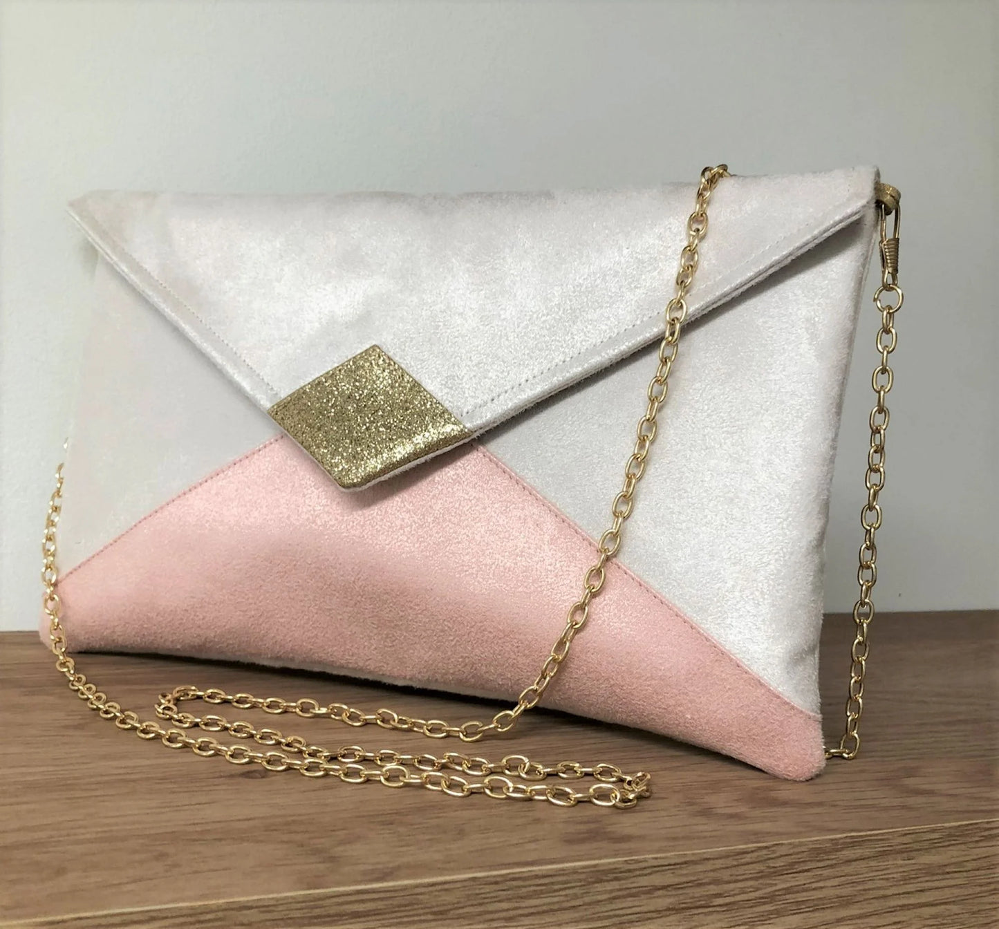 Le sac pochette Isa écru et rose poudré à paillettes dorées.