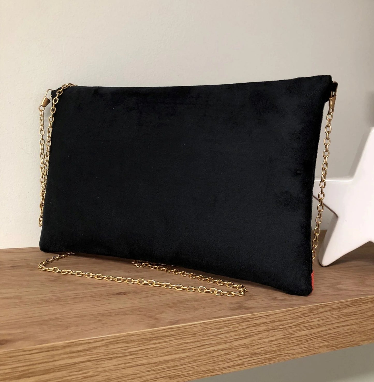 Face arrière du sac pochette Isa noir et corail à paillettes dorées.