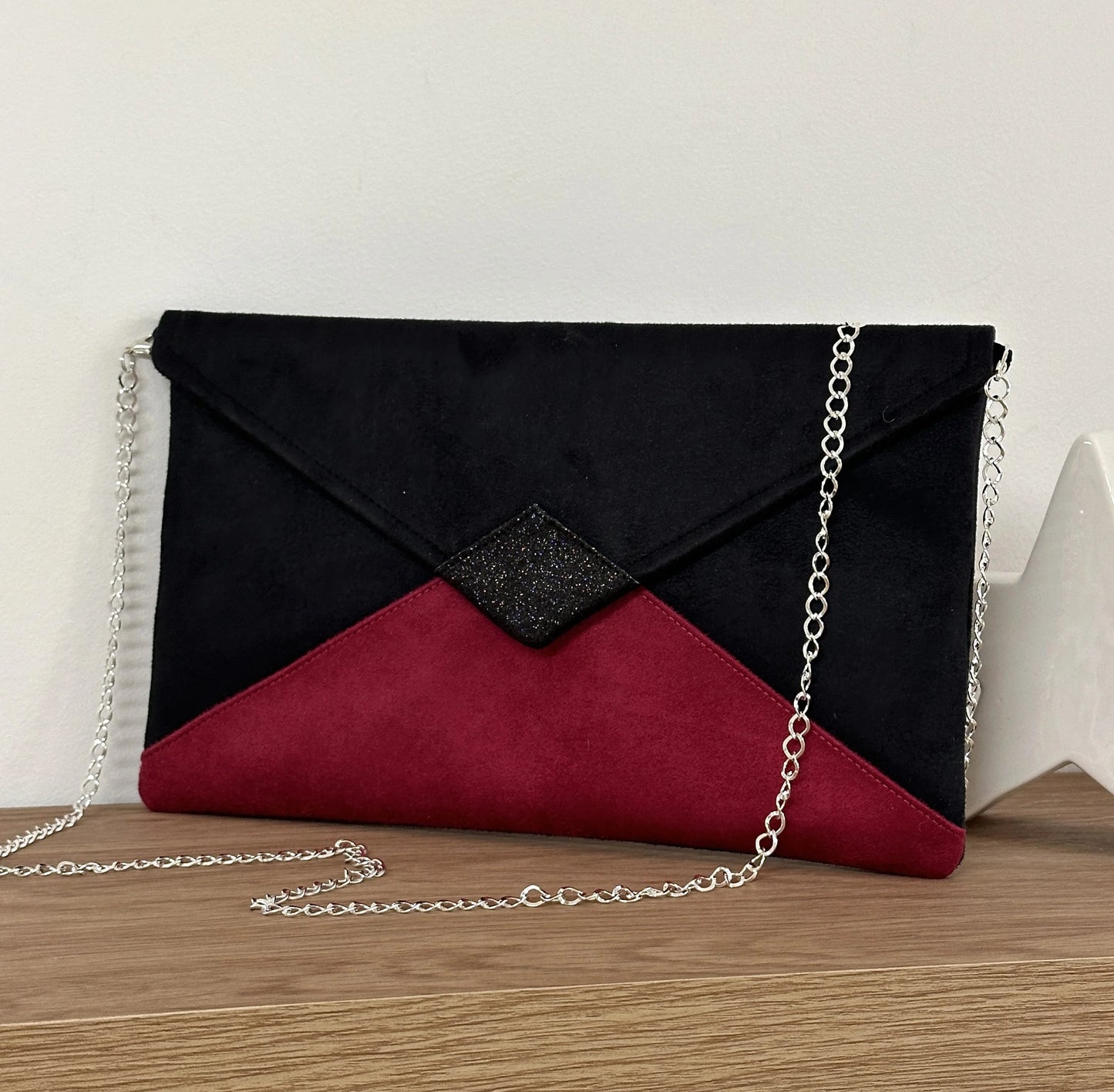 Le sac pochette Isa noir et fuchsia à paillettes avec chainette argentée amovible.