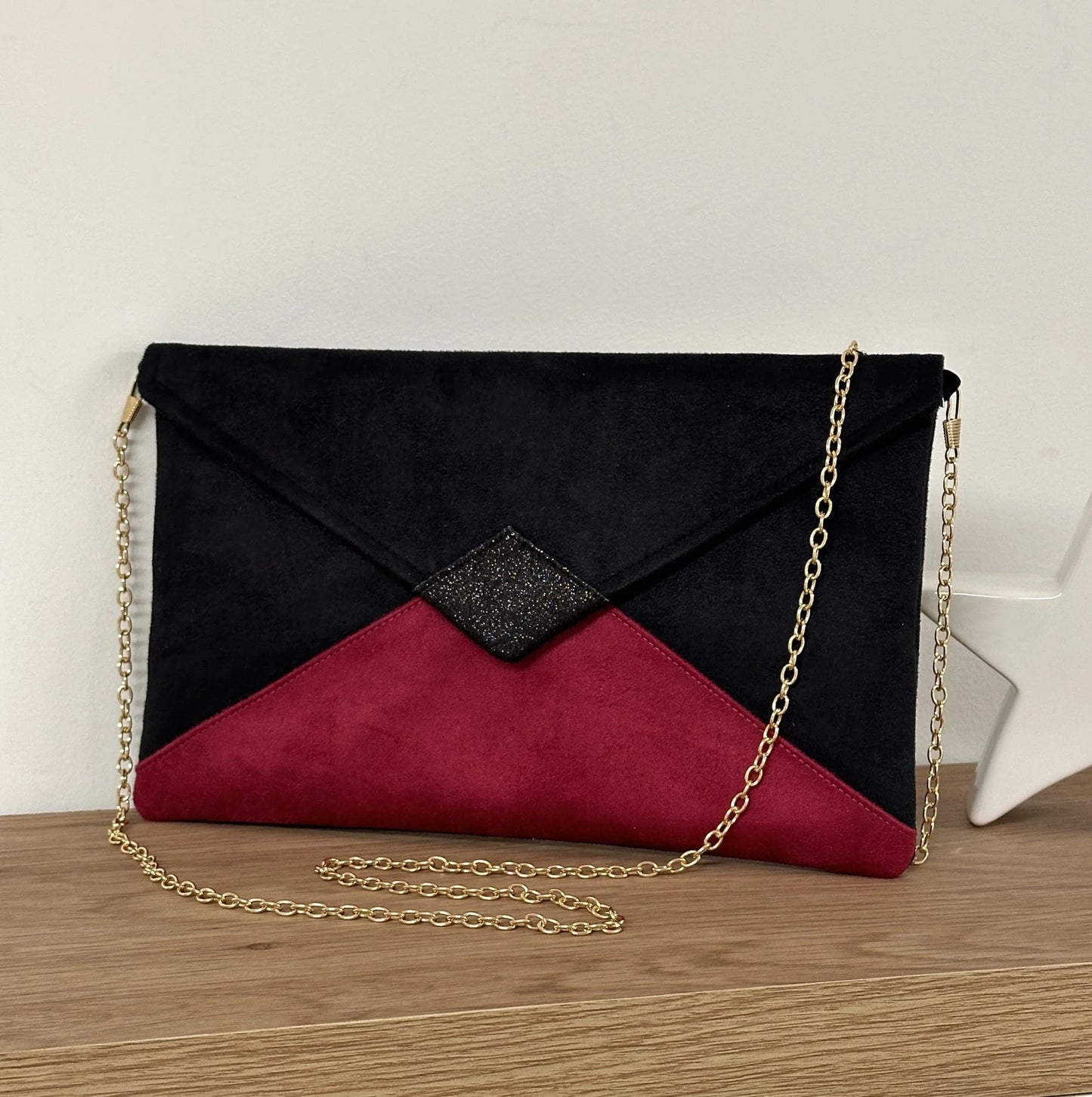 Le sac pochette Isa noir et fuchsia à paillettes avec chainette dorée amovible.