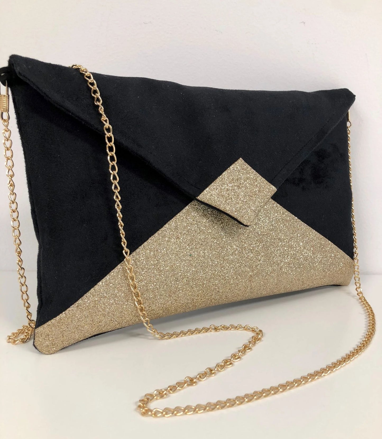 Le sac pochette Isa noir à paillettes dorées, avec chainette dorée amovible.