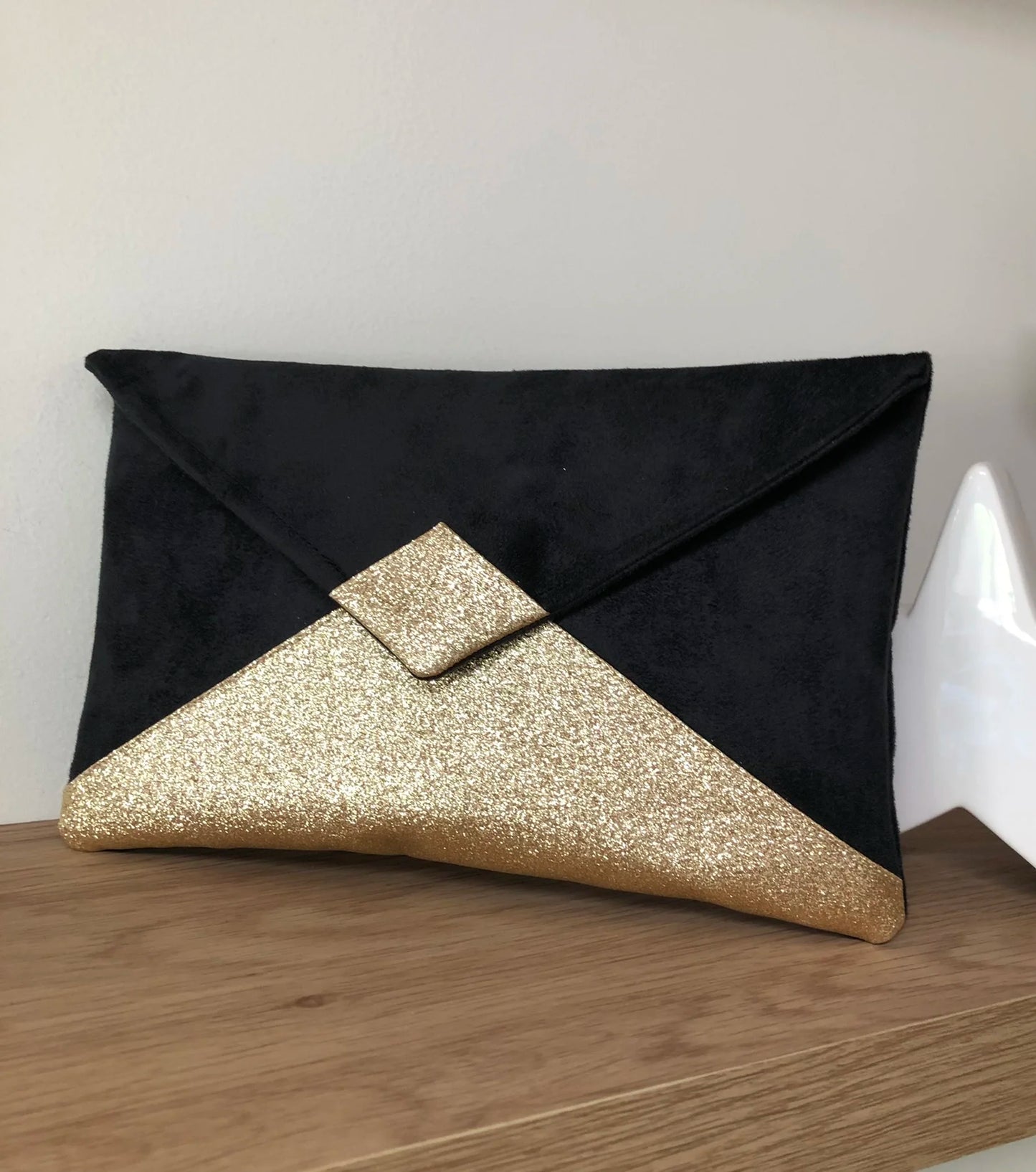Le sac pochette Isa noir à paillettes dorées, sans chainette amovible.