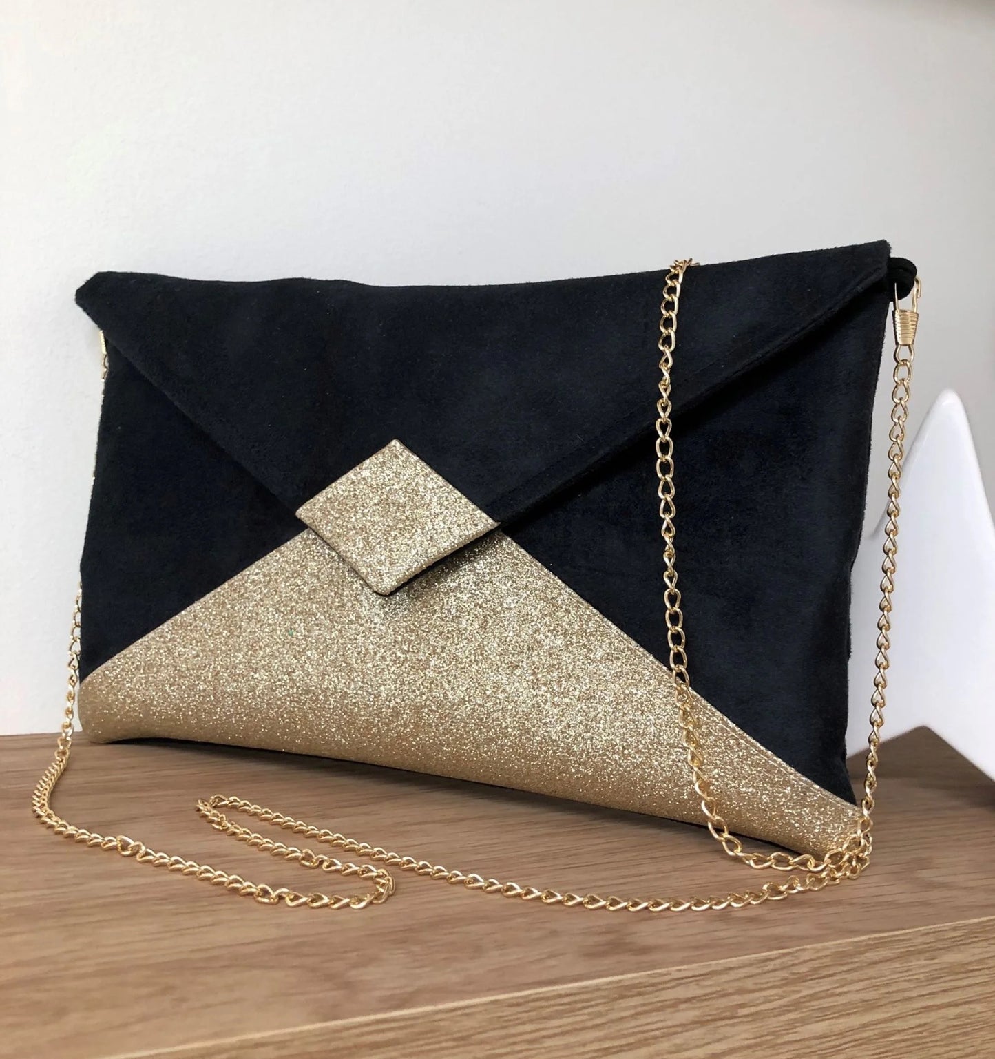 Le sac pochette Isa noir à paillettes dorées, avec chainette amovible.