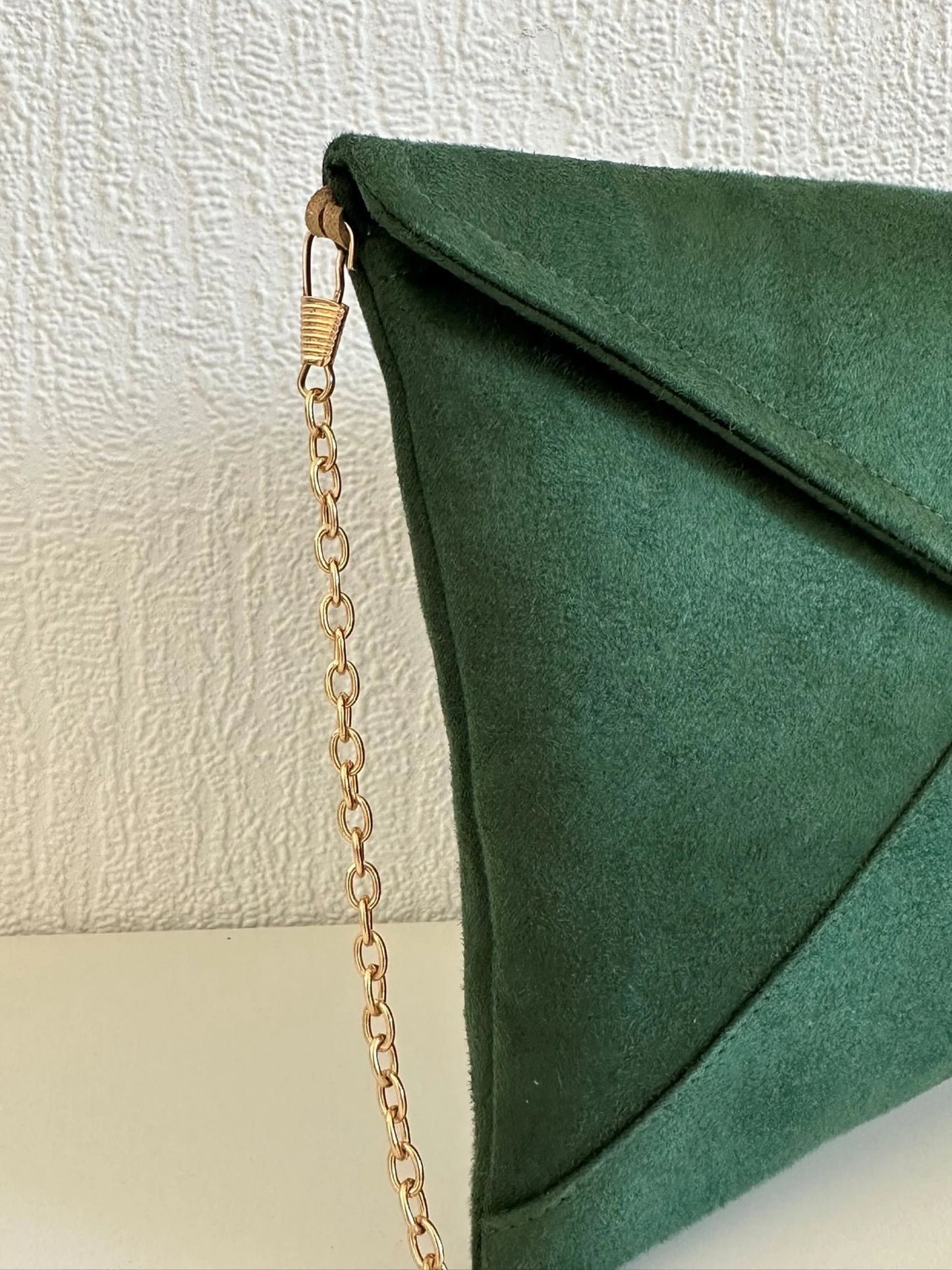 La chainette dorée amovible du sac pochette Isa vert sapin et paillettes dorées.