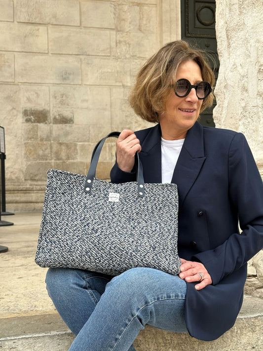 Le sac shopper bleu chiné posé sur les genoux