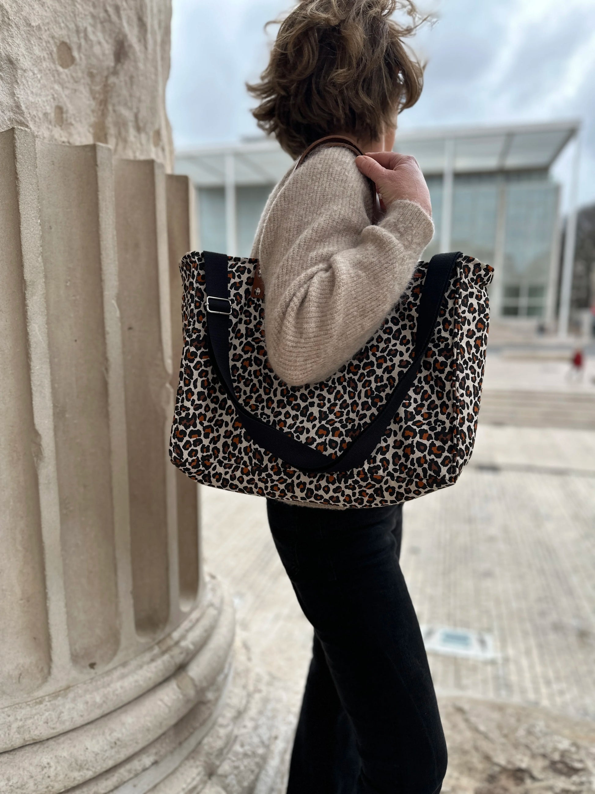 Femme portant le sac Shopper léopard à l'épaule, avec bandoulière amovible réglable.