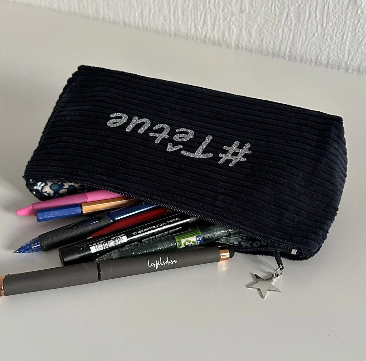 Beaucoup de stylos dans la trousse scolaire en velours bleu personnalisable.