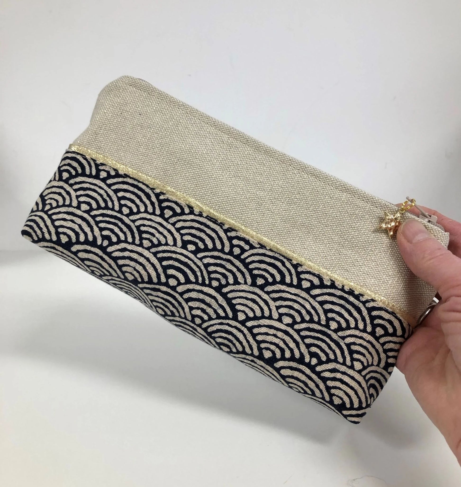 La trousse à stylos en tissu japonais bleu nuit et doré, tenue en main.