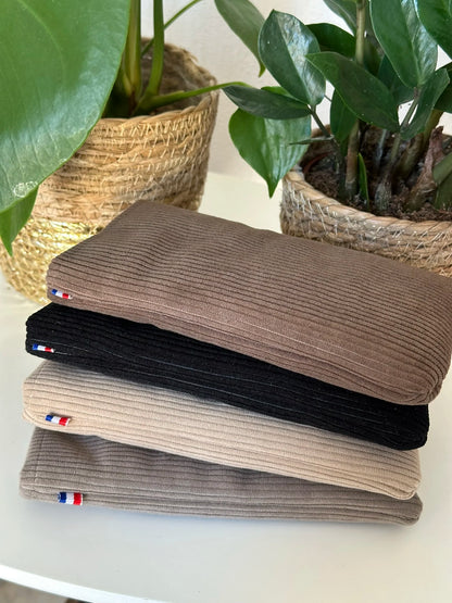 L'étui à lunettes en velours cotelé marron chamois, posé sur le noir, le beige et le taupe.
