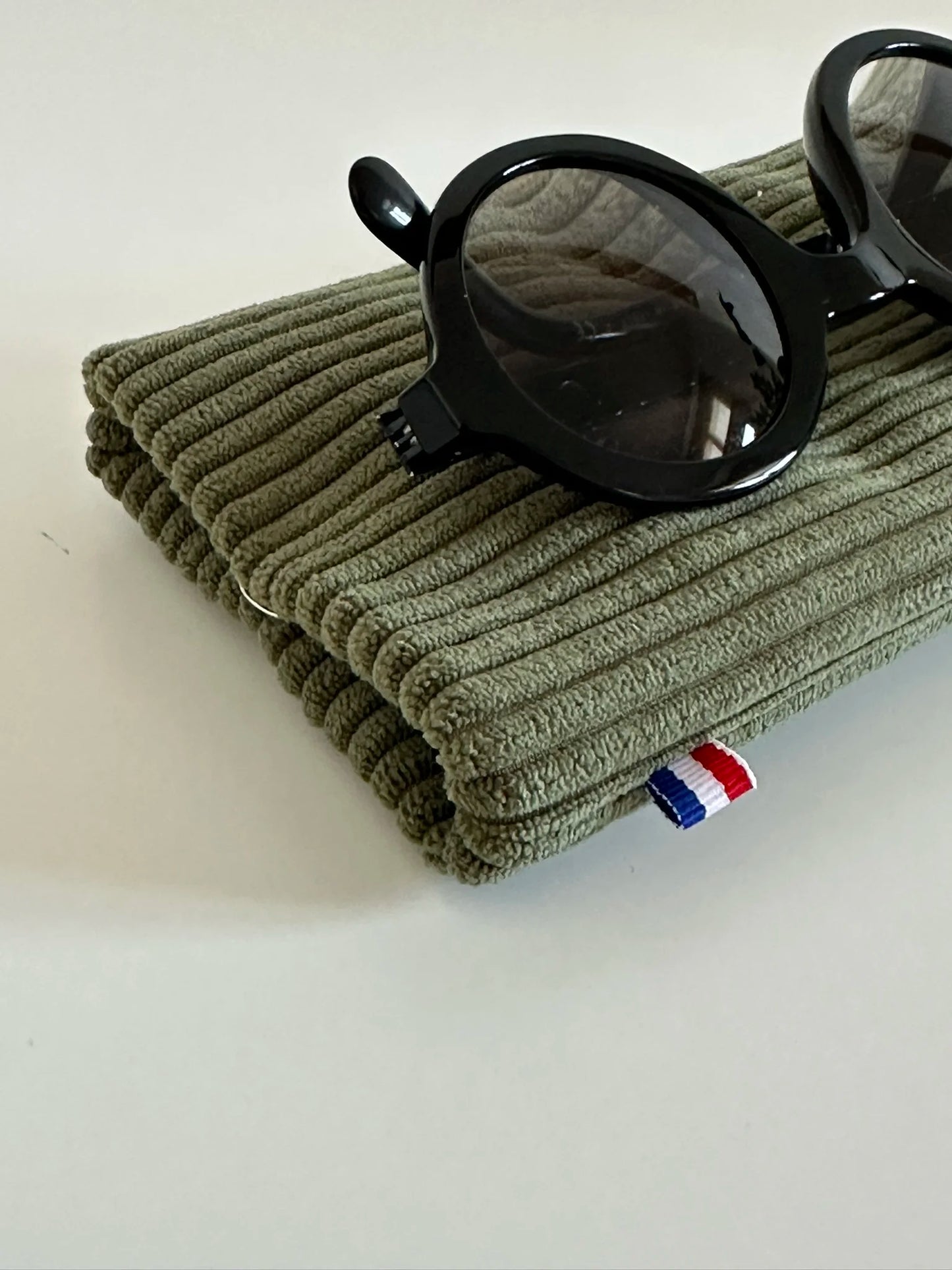 La finition française de l'étui à lunettes en velours cotelé vert armée.
