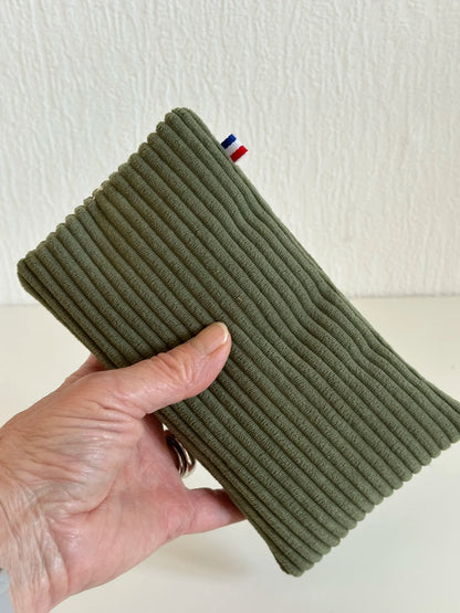 L'étui à lunettes en velours cotelé vert armée, tenu dans la main.