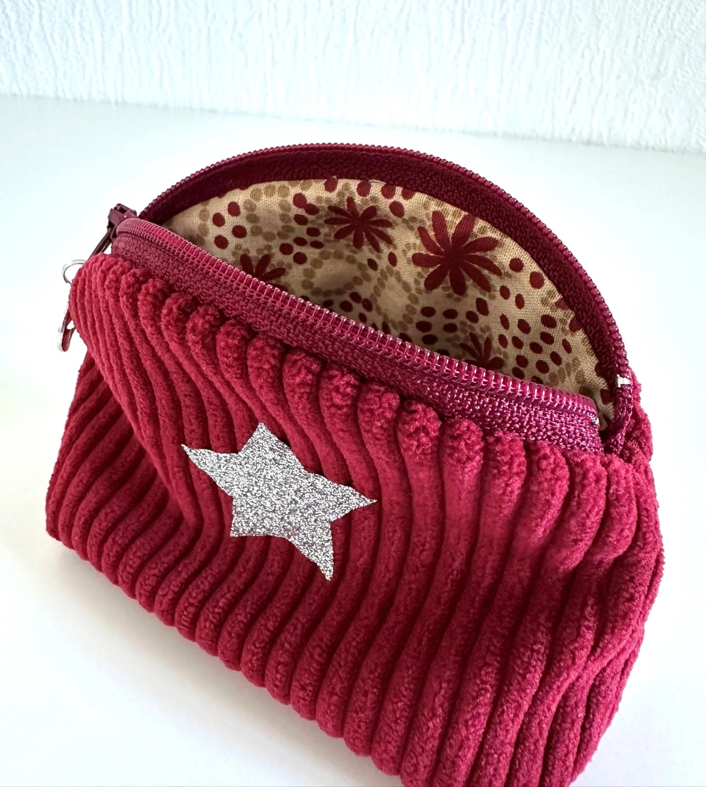 Le petit porte monnaie en velours cotelé bordeaux, ouvert.