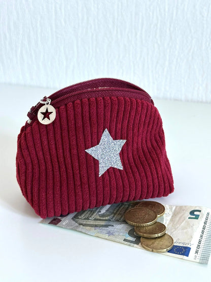 Le petit porte monnaie en velours cotelé bordeaux présenté avec des espèces.