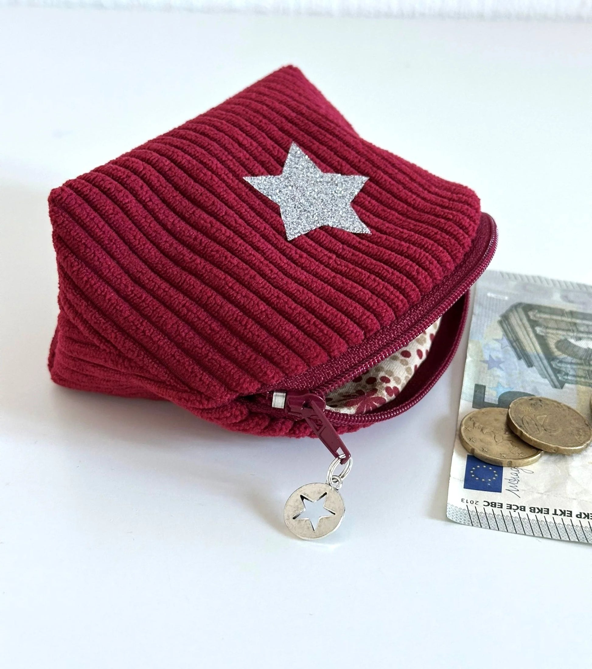 Vue latérale du petit porte monnaie en velours cotelé bordeaux.