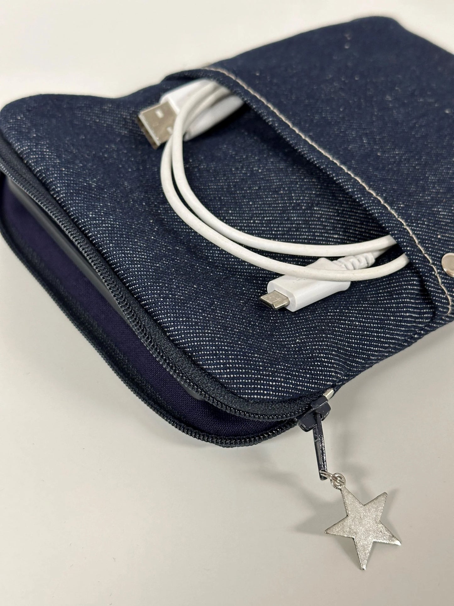 La pochette liseuse en denim brut, entrouverte.