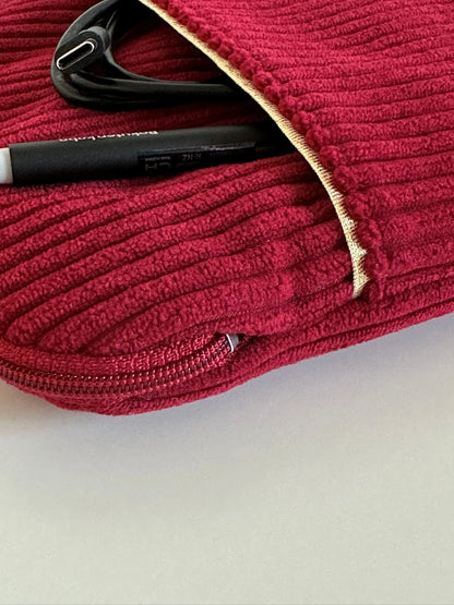 Le liseré doré de la poche avant de la pochette liseuse en velours cotelé bordeaux.