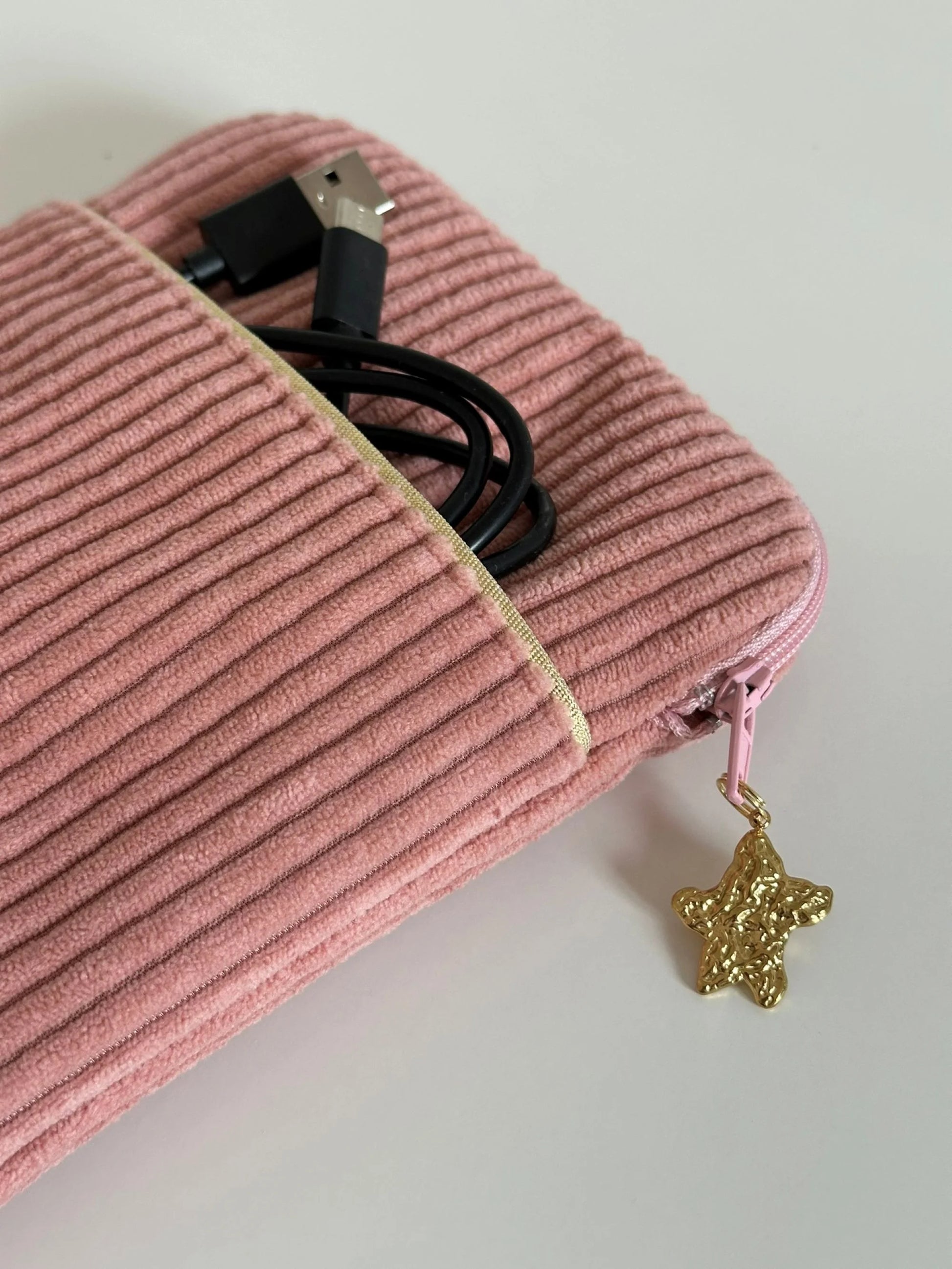 Le liseré doré de la poche avant de la pochette liseuse en velours cotelé rose blush .