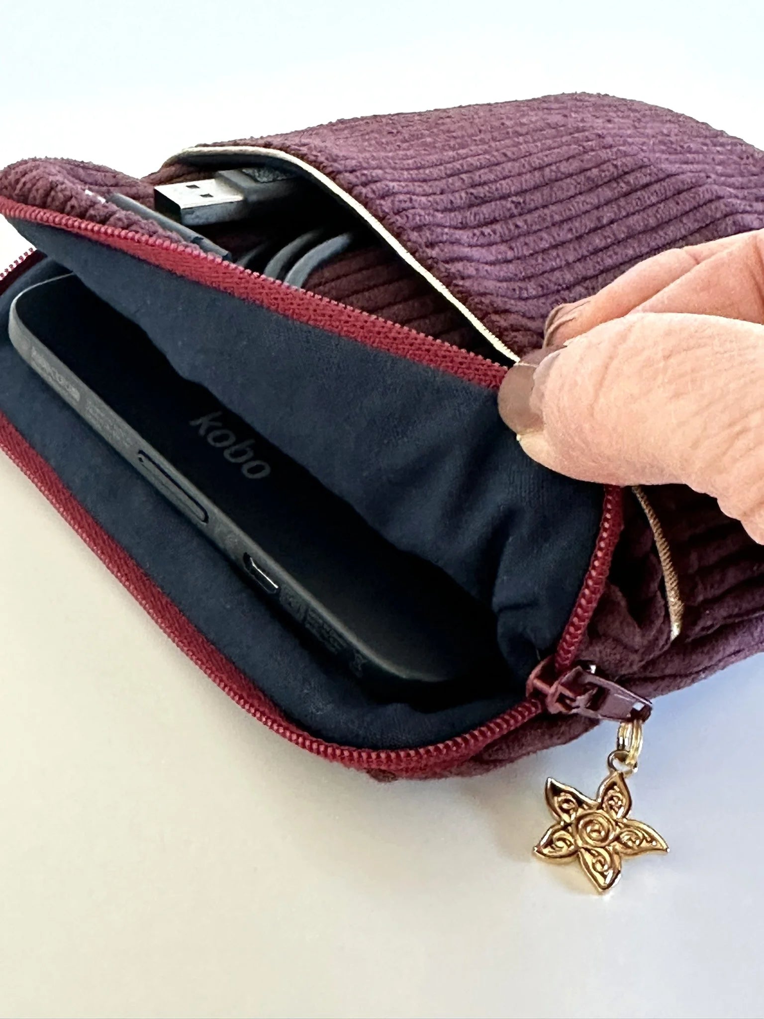 L'ouverture élargie de la pochette liseuse en velours prune.