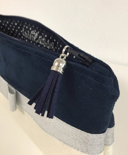 Vue détaillée de la pochette à maquillage bleu marine et blanc à noeud argenté.