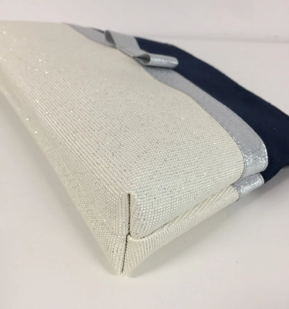 Le fond de la pochette à maquillage bleu marine et blanc à noeud argenté.