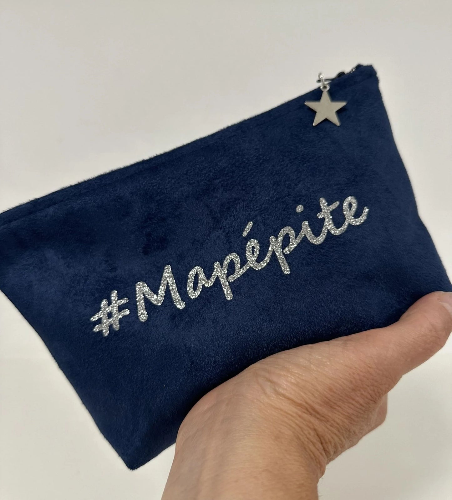 La pochette à maquillage bleu marine à paillettes personnalisable, tenue dans la main.